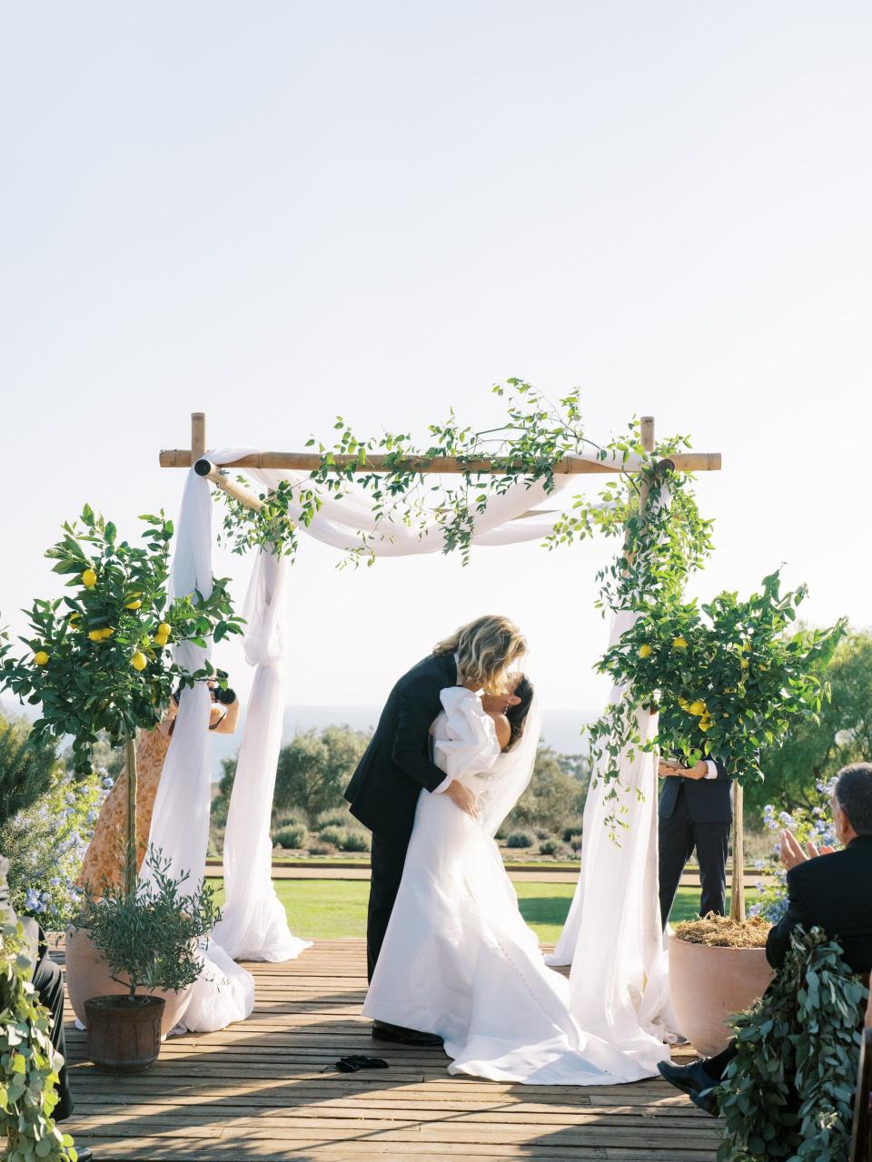 A bride and groom kiss under a huppa at their wedding.