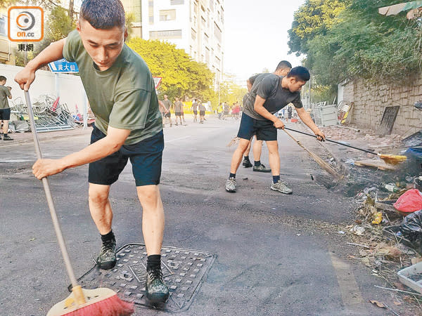 駐港解放軍將道路上的垃圾掃到路邊，令馬路回復暢通。