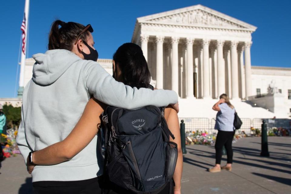 Voters embrace near a makeshift memorial for Rutth Bader Ginsburg at the US supreme court in Washington DC, on 21 September.