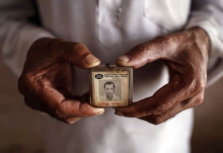 Former maintenance worker, Mohammed Yaqub, poses in his house with his old identity card from the defunct Union Carbide pesticide plant in Bhopal where he once worked November 13, 2014. REUTERS/Danish Siddiqui