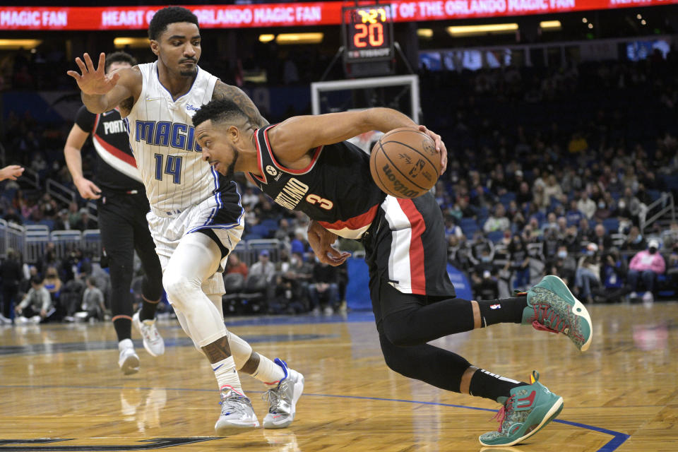 Portland Trail Blazers guard CJ McCollum (3) drives to the basket in front of Orlando Magic guard Gary Harris (14) during the first half of an NBA basketball game, Monday, Jan. 17, 2022, in Orlando, Fla. (AP Photo/Phelan M. Ebenhack)