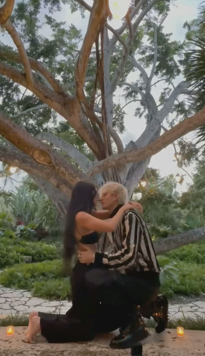 A head-on shot of Megan and MGK both kneeling on the floor