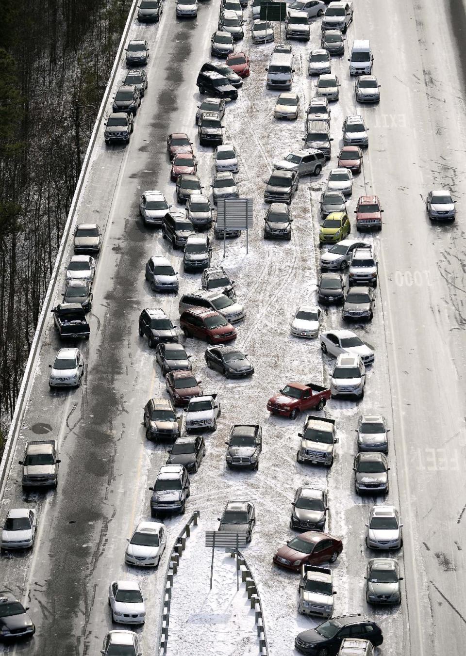 In this aerial photo, abandoned cars at I-75 headed northbound near the Chattahoochee River overpass are piled up in the median of the ice-covered interstate after a winter snow storm , Wednesday, Jan. 29, 2014, in Atlanta. Georgia Gov. Nathan Deal said early Wednesday that the National Guard was sending military Humvees onto Atlanta's snarled freeway system in an attempt to move stranded school buses and get food and water to people. Georgia State Patrol troopers headed to schools where children were hunkered down early Wednesday after spending the night there, and transportation crews continued to treat roads and bring gas to motorists, Deal said. (AP Photo/David Tulis)