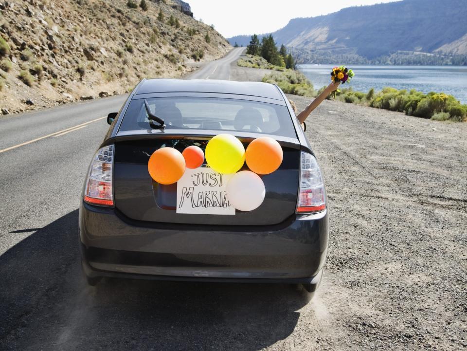 a just married car with balloons dangling from the rear