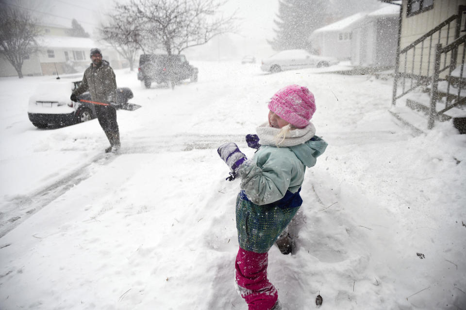 Jared Hanson playfully sprays his daughter, Kaityln, 7, with a shovel full of snow as she builds a snow fort while her clears the sidewalk in front of their home in Bismarck, N.D., Tuesday, April 12, 2022. "This is the first blizzard I have ever seen before," Kaitlyn said. She said she has been in snow storms before, "But this is a real, real, real, real blizzard."(Mike McCleary/The Bismarck Tribune via AP)