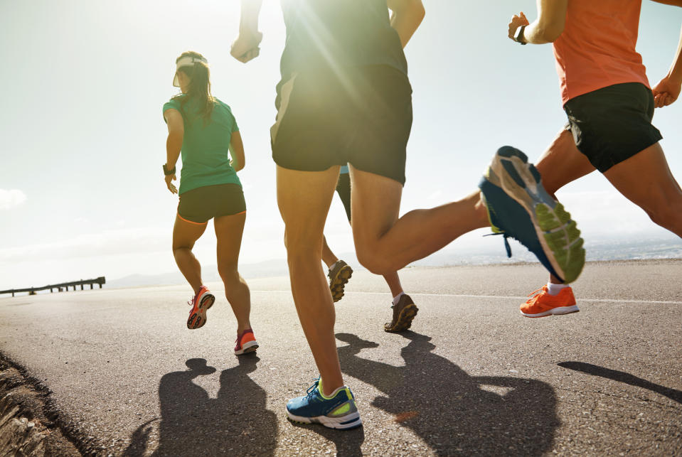 People jogging on a paved road, with shadows cast on the ground