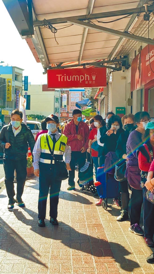 守望相助隊協助藥局維護排隊人潮秩序，引起部分隊員反彈。（呂筱蟬攝）