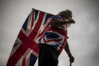 A man carries a Union flag marking the death of Prince Philip, in Gibraltar, Saturday April 10, 2021. Britain's Prince Philip, the irascible and tough-minded husband of Queen Elizabeth II who spent more than seven decades supporting his wife in a role that mostly defined his life, died on Friday. (AP Photo/Javier Fergo)