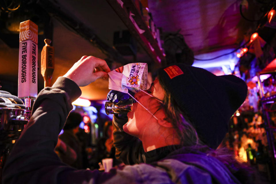 Bartender Cassandra Paris takes farewell a shot at an early closing time at 169 bar with patrons Monday, March 16, 2020, in New York. New York leaders took a series of unprecedented steps Sunday to slow the spread of the coronavirus, including canceling schools and extinguishing most nightlife in New York City. (AP Photo/John Minchillo)