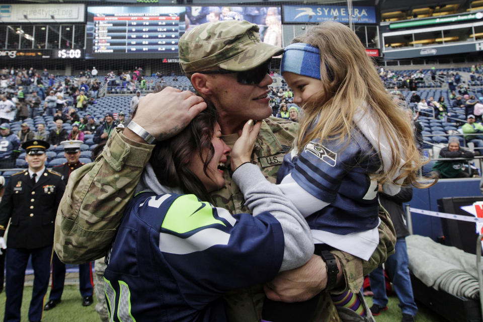 <p>United States Army Sgt. Zach Ames, center, who has been on a one-year deployment to Afghanistan, surprises his wife, Bri Ames, left, and their daughter Emersyn, right, with a reunion prior to an NFL football game between the New York Jets and the Seattle Seahawks on Veterans Day, Sunday, Nov. 11, 2012, in Seattle. (AP Photo/Elaine Thompson) </p>