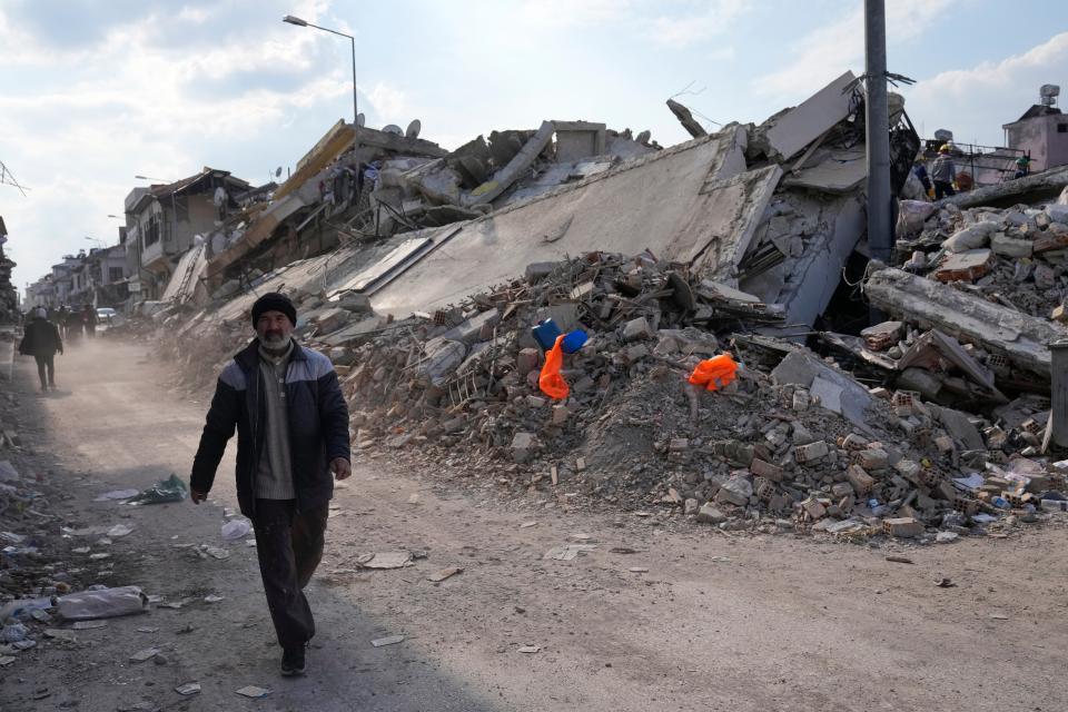 A man passes collapsed buildings in Antakya, Turkey, Saturday, Feb. 11, 2023. Emergency crews made a series of dramatic rescues in Turkey on Friday and Saturday, pulling several people from the rubble days after a catastrophic 7.8-magnitude earthquake killed thousands in Turkey and Syria.