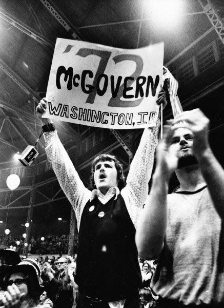 Jim Dougall of Washington, Iowa, holds up a sign of support as he and other George McGovern supporters lead a cheer at a “people’s dinner” for 5,000.