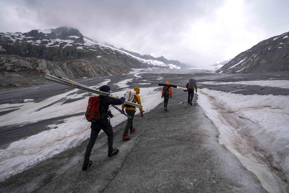 Swiss Federal Institute of Technology glaciologist and head of the Swiss measurement network 'Glamos', Matthias Huss, second right, walks up to the Rhone Glacier with his team near Goms, Switzerland, Friday, June 16, 2023. Now dwindling at an alarming rate because of human-caused climate change, the group monitors what is left of the country's glaciers in an attempt to slow their demise. (AP Photo/Matthias Schrader)