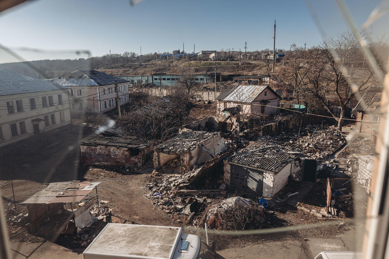 Damaged houses due to Russian shelling are seen through a broken window in Bakhmut, Ukraine, on Jan. 24, 2023