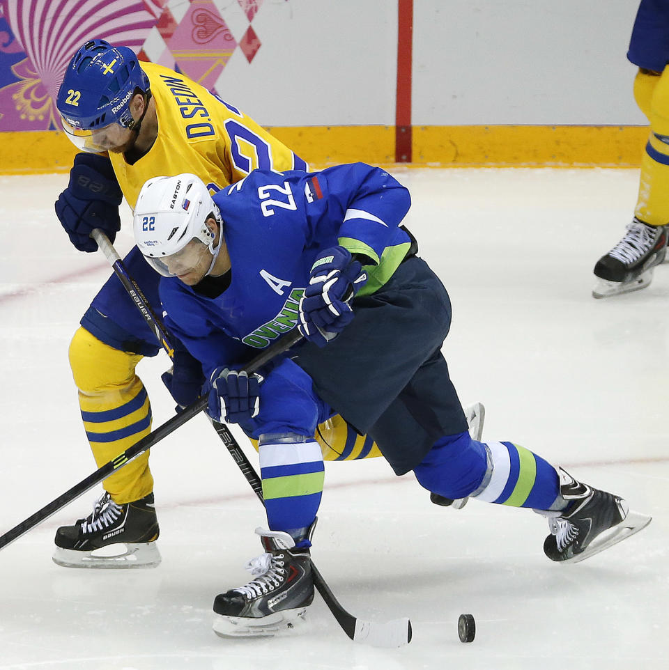 Sweden forward Daniel Sedin and Slovenia forward Marcel Rodman battle for the puck in the second period of a men's quarterfinal ice hockey game at the 2014 Winter Olympics, Wednesday, Feb. 19, 2014, in Sochi, Russia. (AP Photo/Mark Humphrey)
