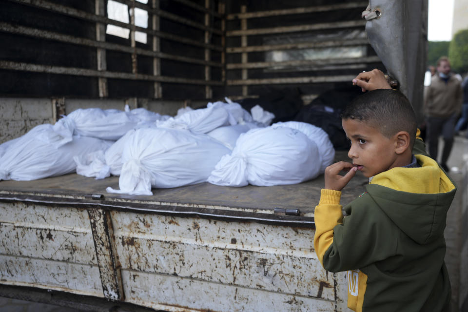 A Palestinian boy stands by the bodies of relatives killed in the Israeli bombardments of the Gaza Strip in front of the morgue of the Al Aqsa Hospital in Deir al Balah on Saturday, Feb. 24, 2024. (AP Photo/Adel Hana)