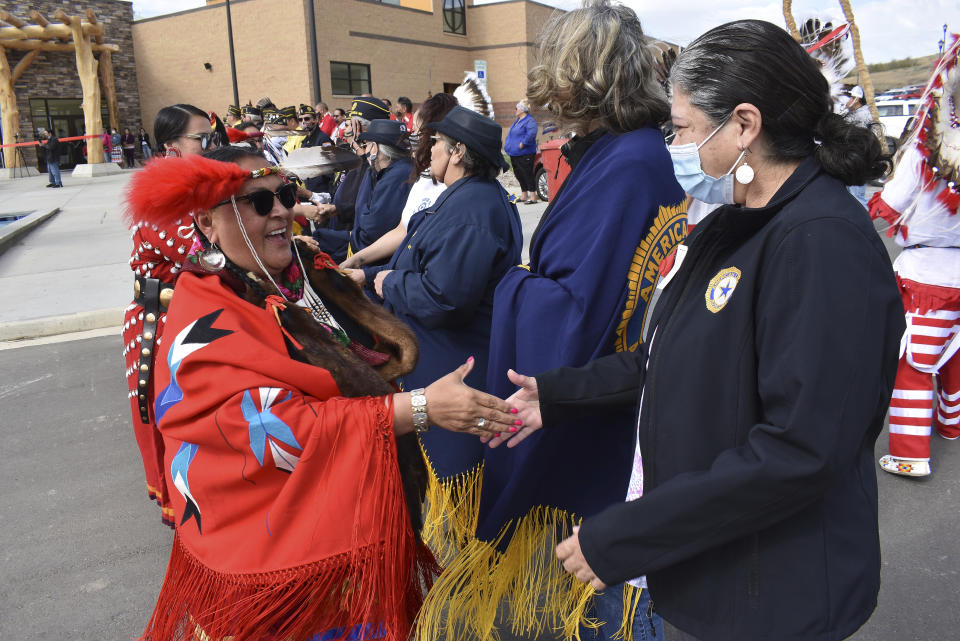 In this Wednesday, May 19, 2021, photo, Clarine DeGroot, left, of the Enemy Women Society traditional group is seen shaking the hand of a woman from the American Legion at an event marking the opening of the MHA Nation Interpretive Center, a cultural center and museum on the Fort Berthold Indian Reservation in New Town, North Dakota. The $30 million cultural center in New Town pieces together the tribes’ fractured past through displays and artifacts. (AP Photo/Matthew Brown)