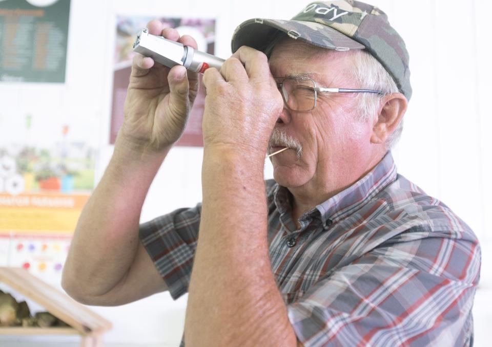 John Grafton of the Ohio State Beekeepers Association uses a refractometer to read the moisture level of honey while judging entries at the Stark County Fair on Tuesday.
