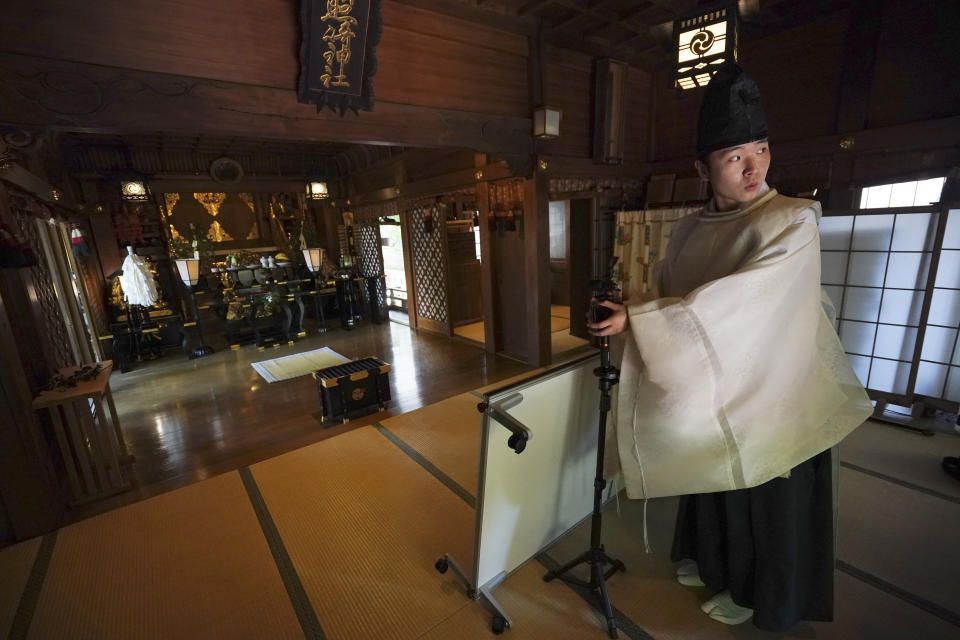 In this May 8, 2020, photo, a priest prepares a livestream prayer during a 10-day trial of "online shrine" visit program at Onoterusaki Shrine in downtown Tokyo, allowing its visitors to join rituals from their homes. The shrine also accepted from worshipers their prayer messages, which were printed on a virtual wooden tablet each and offered to the Shinto gods to keep away evil spirits and the epidemic. (AP Photo/Eugene Hoshiko)