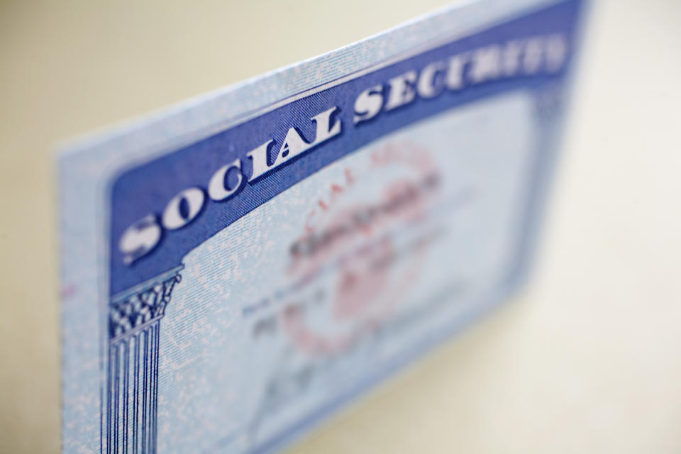 A Social Security card standing up on a table, with the name and number blurred out.