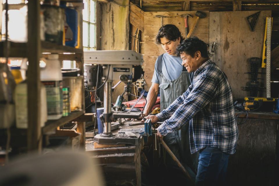 father teaching adult son in farm workshop