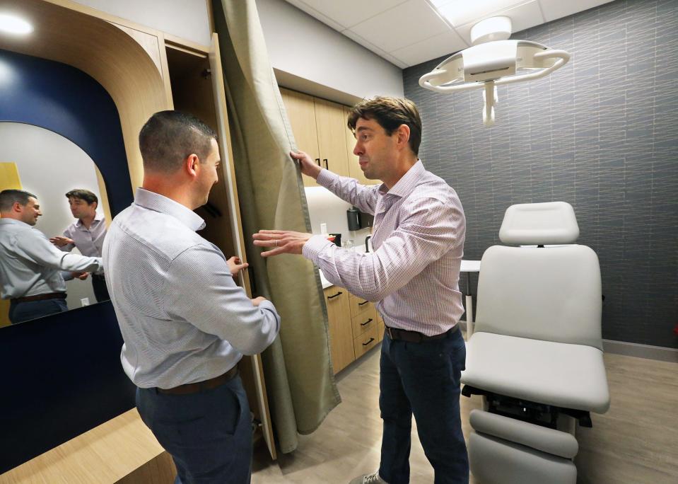 Ben Collins, chief growth officer at Optima Dermatology, left, and CEO Max Puyanic show off a privacy curtain within one of the exam rooms at the new Stratham facility July 13, 2023.