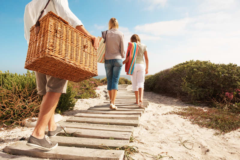 Family taking a walk down to the beach for a picnic - cropped rear view