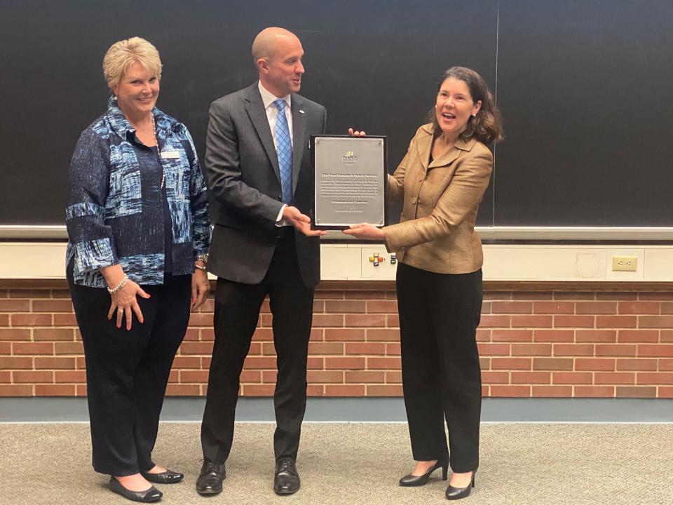 Kim Ryan (left) and Kevin Buchler (middle) present Alyssa Wilcox (right) with a plaque in honor of Coperion and Hillenbrand's donation of an extruder machine to Purdue.