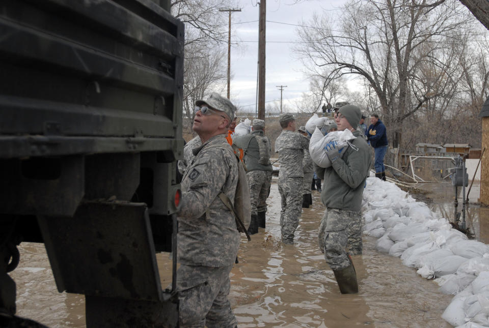 CORRECTS YEAR TO 2014 This March 9, 2014 photo provided by the Wyoming National Guard shows Guard members, with the 153rd Airlift Wing and the 920th Forward Support Company, civilian volunteers and town employees forming a chain to deliver sandbags to flooding houses in Graybull, Wyo. (AP Photo/Wyoming National Guard)