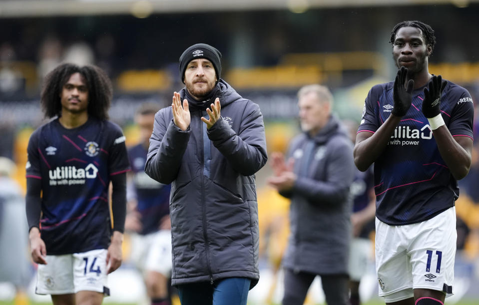 Luton Town's Tom Lockyer, centre, and team-mate Elijah Adebayo applaud the fans following the Premier League match between Wolverhampton Wanderers and Luton Town at Molineux Stadium, Wolverhampton, England, Saturday April 27, 2024. Tom Lockyer, the Premier League player who suffered an onfield cardiac arrest earlier this season, says he is “at peace” if he is forced to retired from the sport. (Nick Potts/PA via AP)