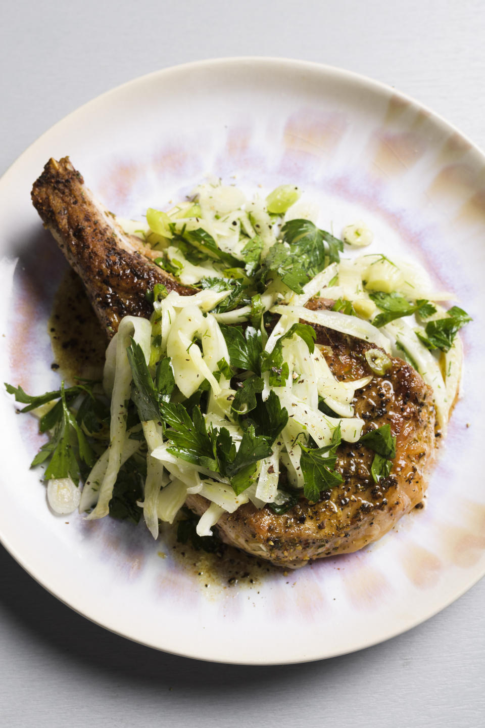 This image released by Milk Street shows a recipe for seared pork chops with a fennel and herb salad. (Milk Street via AP)