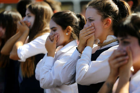 Demonstrators cover their mouths during a protest calling for changes in the education system in Santiago, Chile April 11, 2017. REUTERS/Ivan Alvarado