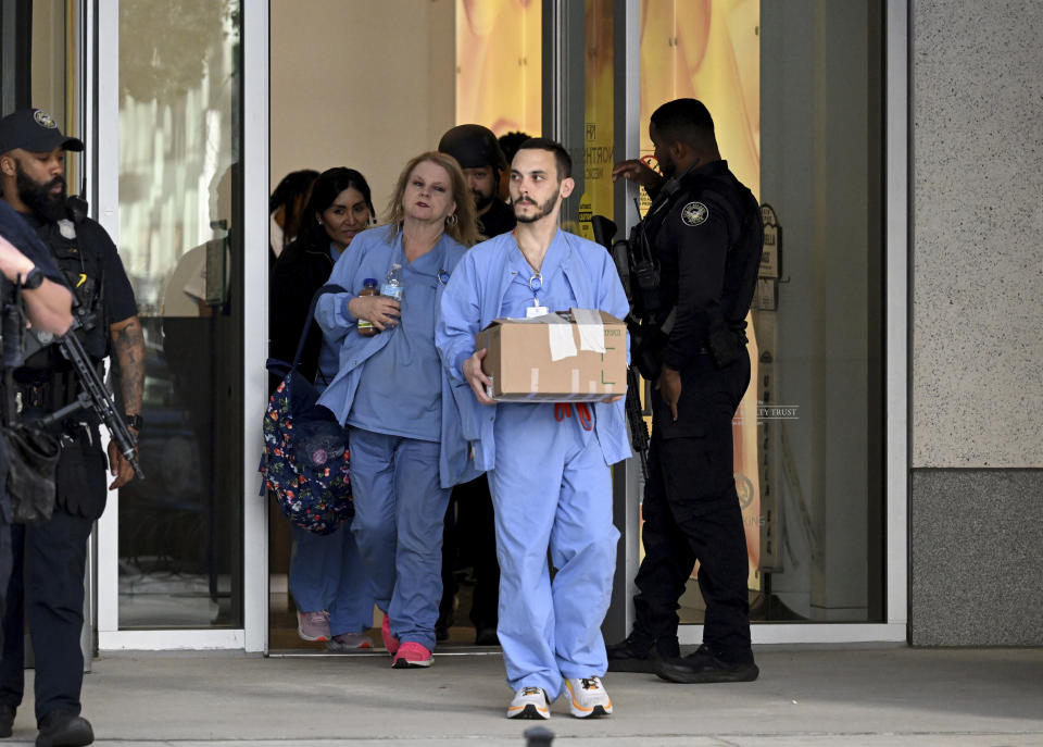 Law enforcement personnel wath as healthcare workers leave the Northside Hospital Midtown medical office building, Wednesday, May 3, 2023, in Atlanta, where five people were shot. (Hyosub Shin/Atlanta Journal-Constitution via AP)