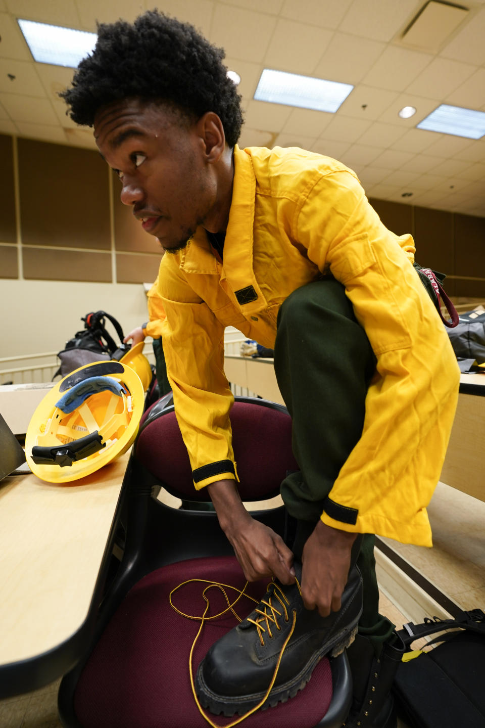 Ben Malone laces up his boots as he prepares for a wildland firefighter training Friday, June 9, 2023, in Huntsville, Ala. A partnership between the U.S. Forest Service and four historically Black colleges and universities is opening the eyes of students of color who had never pictured themselves as fighting forest fires. (AP Photo/George Walker IV)