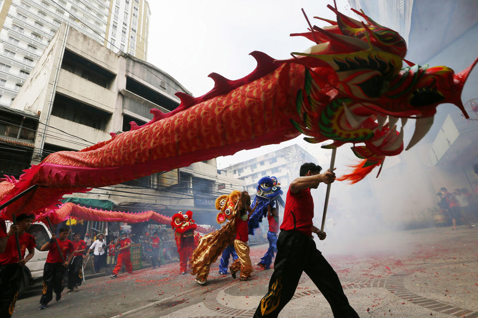 Dragon and lion dancers perform amidst exploding firecrackers in front of a business establishment in celebration of the Chinese Lunar New Year, Saturday, Jan. 28, 2017, in the Chinatown area of Manila, Philippines. This year is the Year of the Rooster on the Chinese lunar calendar. (AP Photo/Bullit Marquez)