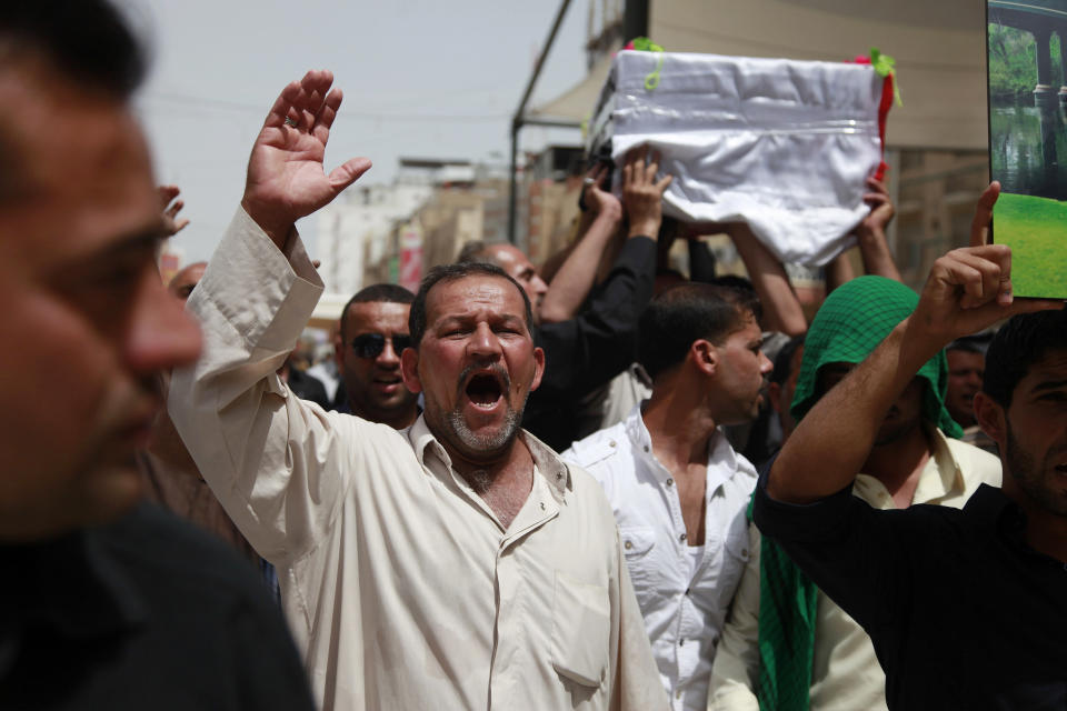 Mourners chant slogans against the al-Qaida breakaway group Islamic State of Iraq and the Levant (ISIL), while carrying a flag-draped coffin of Shawki Rahim during his funeral procession in Najaf, 100 miles (160 kilometers) south of Baghdad, Iraq, Thursday, April 17, 2014. The Iraqi Army officer was killed during clashes with al-Qaida fighters in Hillah last night, his family said. (AP Photo/Jaber al-Helo)