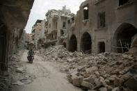 A Syrian man rides his motorbike past destroyed buildings on May 2, 2016, in Aleppo's Bab al-Hadid neighbourhood which was targeted recently by regime air strikes