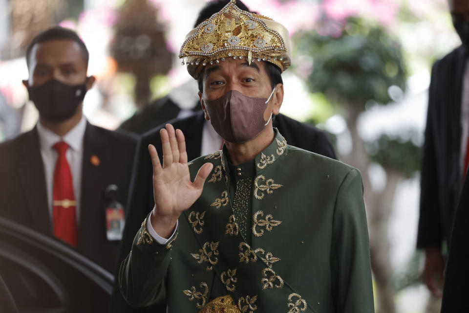 Indonesian President Joko Widodo, wearing traditional outfit from Bangka Belitung, waves at reporters after delivering his annual state address ahead of the country's Independence Day, at the parliament building in Jakarta, Indonesia, Tuesday, Aug. 16, 2022. (Willy Kurniawan/Pool Photo via AP)