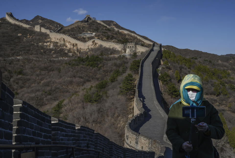 A woman wears a protective mask as she takes a photo on a nearly empty section of the Great Wall on March 27, 2020, near Badaling in Beijing, China.