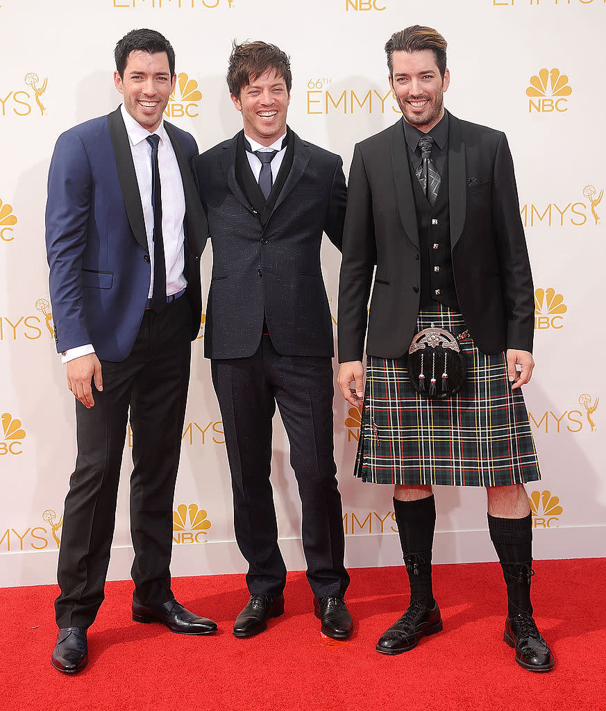 Jonathan Scott, JD Scott, and Drew Scott smile in stylish suits and a kilt on the red carpet at the 66th Emmy Awards