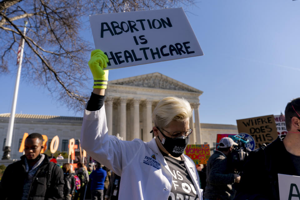 FILE - A woman holds a poster that reads "Abortion is Healthcare" as abortion rights advocates and anti-abortion protesters demonstrate in front of the U.S. Supreme Court, Dec. 1, 2021, in Washington, as the court hears arguments in a case from Mississippi, where a 2018 law would ban abortions after 15 weeks of pregnancy, well before viability. As the Supreme Court court weighs the future of the landmark 1973 Roe v. Wade decision, a resurgent anti-abortion movement is looking to press its advantage in state-by-state battles while abortion-rights supporters prepare to play defense. (AP Photo/Andrew Harnik, File)