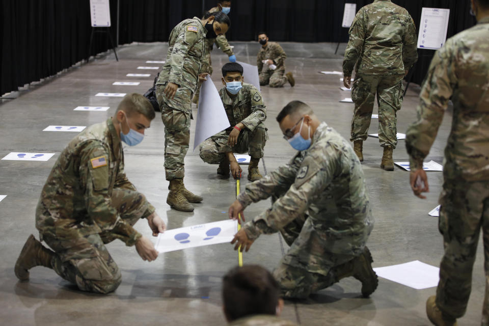 Members of the Nevada National Guard install social distancing stickers while setting up a new temporary coronavirus testing site Monday, Aug. 3, 2020, in Las Vegas. (AP Photo/John Locher)