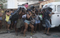 Squatters take cover from stun grenades and tear gas during an eviction in Rio de Janeiro, Brazil, Thursday, April 10, 2014. Squatters in Rio de Janeiro are clashing with police after a Brazilian court ordered that 5,000 people be evicted from abandoned buildings of a telecommunications company. Officers have used tear gas and stun grenades to try to disperse the families.(AP Photo/Silvia Izquierdo)