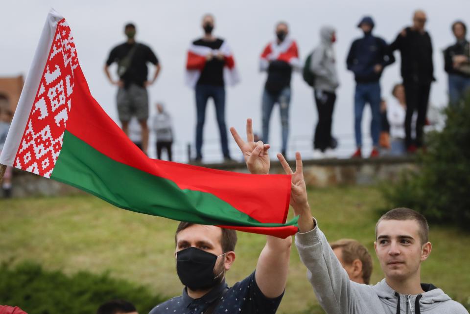 CORRECTING COUNTRY IN CAPTION TO BELARUS - People with Belarusian National flag gather in a street protesting the election results in Minsk, Belarus, Wednesday, Aug. 12, 2020. The demonstrators are contesting the official count showing President Alexander Lukashenko winning a sixth term with 80% of Sunday's vote, with crowds taking to the streets every night since to demand a recount. (AP Photo)