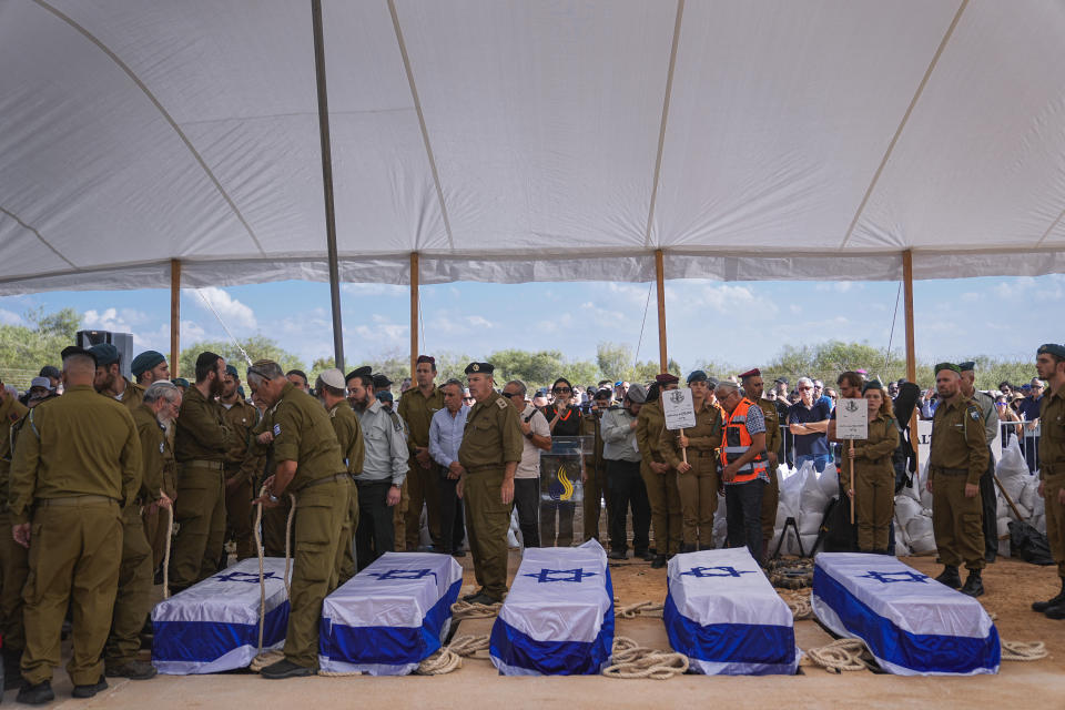 Un grupo de dolientes se congregan alrededor de los féretros de cinco miembros de la familia Kotz durante su funeral en Gan Yavne, Israel, el 17 de octubre de 2023. (AP Foto/Ohad Zwigenberg)