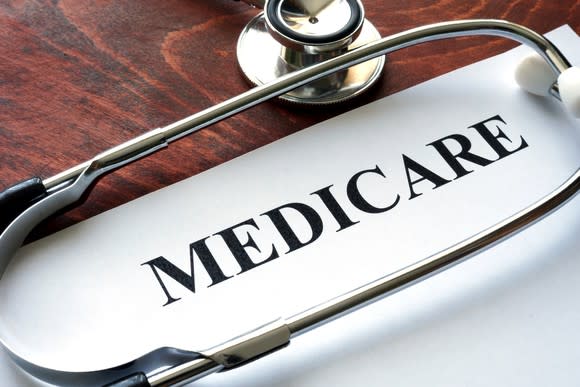 Sheet with Medicare on it lying on a wood table with a stethoscope.