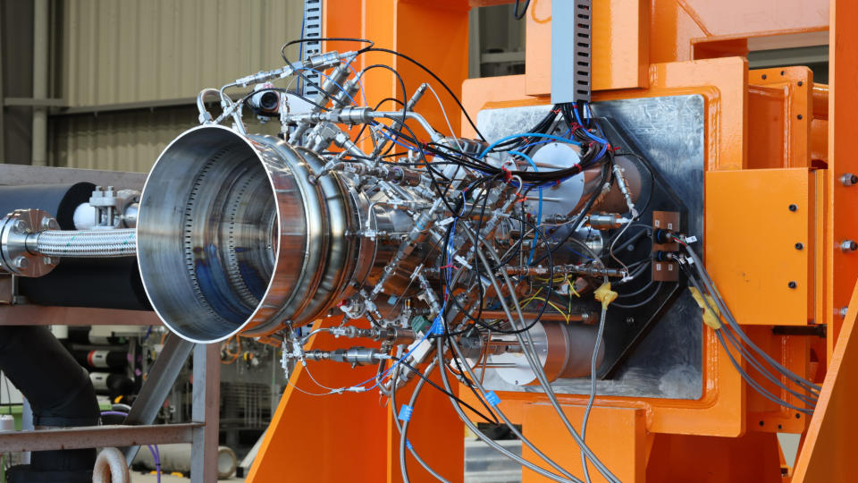 closeup of a rocket nozzle in an orange test stand.