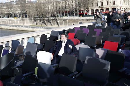 A demonstrator, dressed as a symbolic banker, sits on a chair next to empty ones that were stolen from bank offices in France to protest against the banking system and tax fraud, and installed on a bridge near the courts in Paris, France, February 8, 2016. REUTERS/Charles Platiau