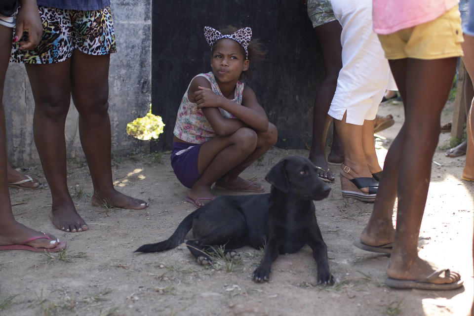 A girl waits for food donated by the Covid Without Hunger organization in the Jardim Gramacho slum of Rio de Janeiro, Brazil, Saturday, May 22, 2021. As incomes fall, prices are surging, which means the disadvantaged are doubly squeezed. (AP Photo/Silvia Izquierdo)