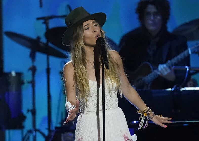 Lauren Daigle wears a large-brimmed hat while singing onstage